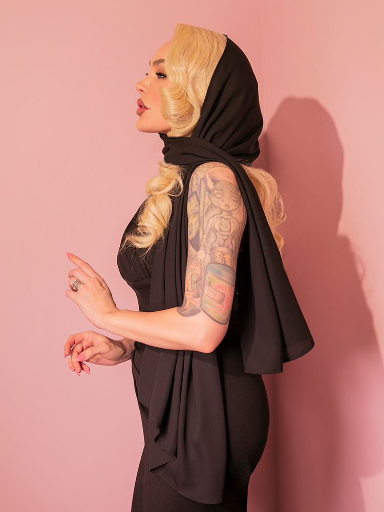 The striking lady model exhibits the black chiffon scarf, harking back to the 1950s, from the vintage brand Vixen Clothing.