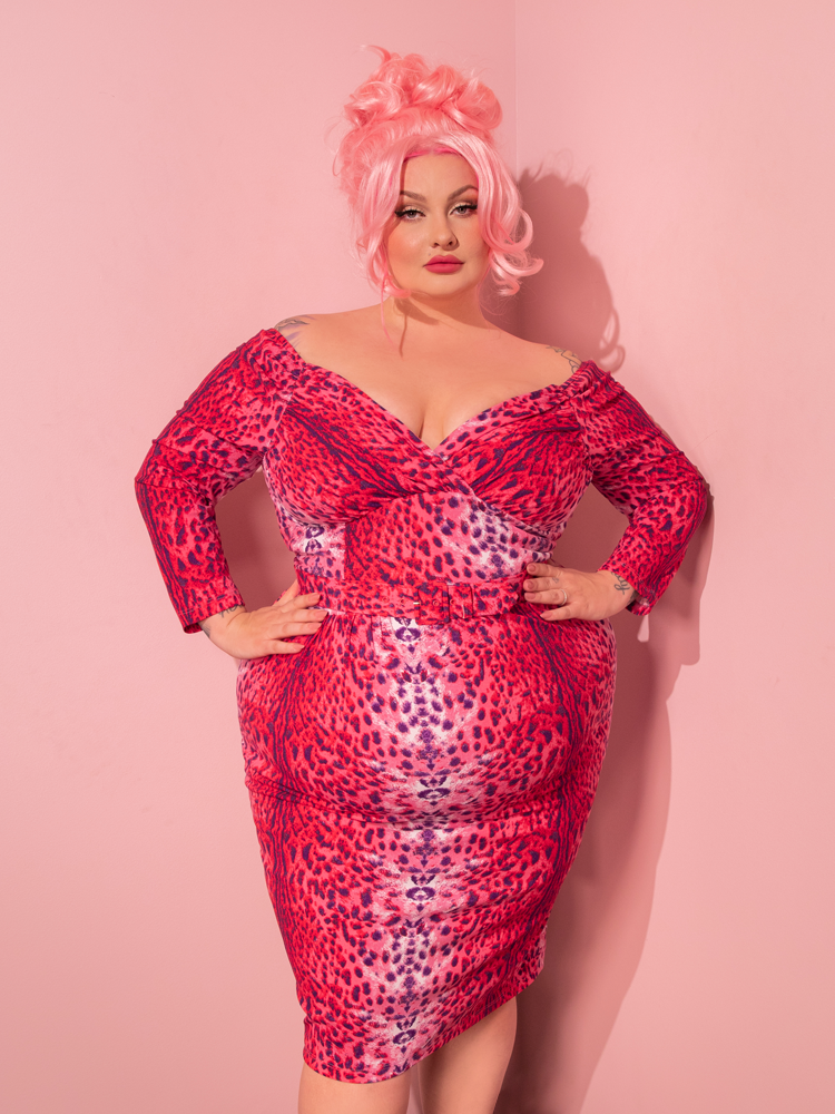 Immerse yourself in nostalgia as a beautiful model graces the scene, wearing the Starlet Wiggle Dress and Scarf in Pink Leopard Print, handcrafted by the retro clothing brand Vixen Clothing.