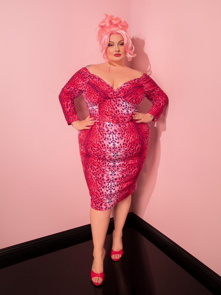 Discover the epitome of retro glamour as a stunning model struts her stuff in the Starlet Wiggle Dress and Scarf in Pink Leopard Print, crafted by the esteemed Vixen Clothing label.