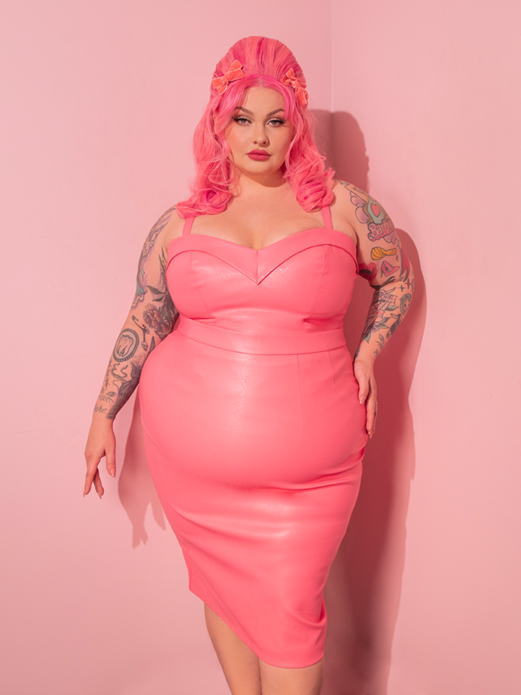 Step back in time and witness the mesmerizing allure of the gorgeous model, effortlessly flaunting the Bad Girl Maneater Top in Flamingo Pink Vegan Leather, an irresistible masterpiece by Vixen Clothing, the epitome of retro fashion.