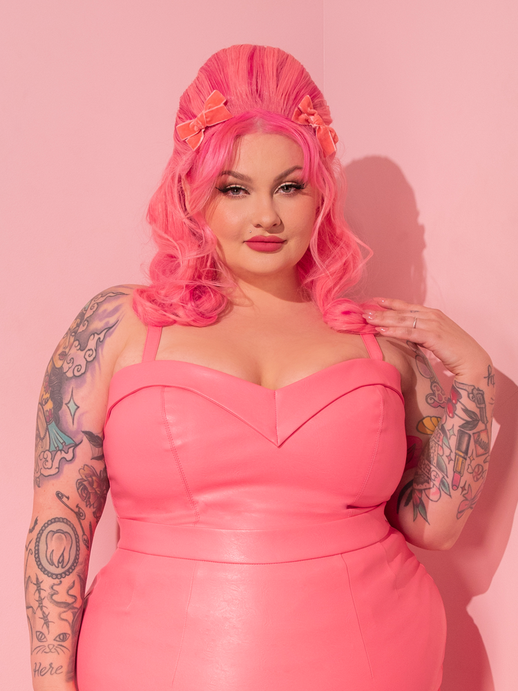 Behold the stunning retro queen, gracefully showcasing the brand new Bad Girl Maneater Top in Flamingo Pink Vegan Leather, straight from the vintage-inspired fashion house, Vixen Clothing.