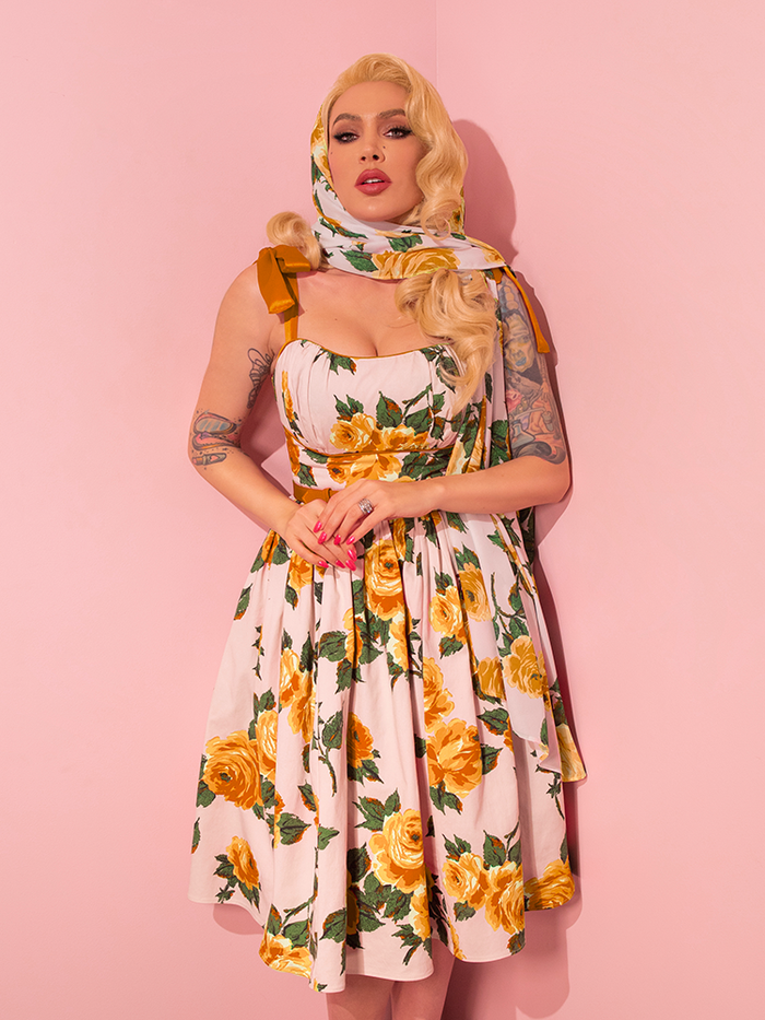Micheline Pitt showcases a range of poses as she models the 1950s Swing Sundress and Scarf in Yellow Vintage Roses from the retro apparel brand Vixen Clothing.