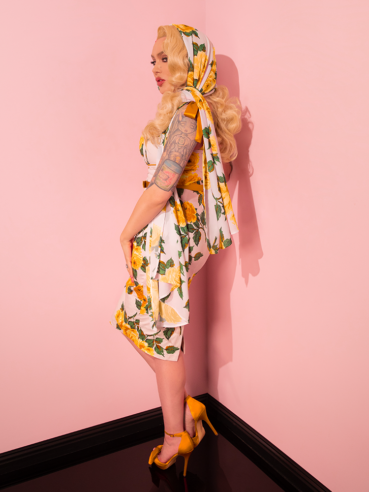 Displaying versatility, Micheline Pitt models the 1950s Wiggle Sundress and Scarf in Yellow Vintage Roses from Vixen Clothing, striking a variety of captivating poses.