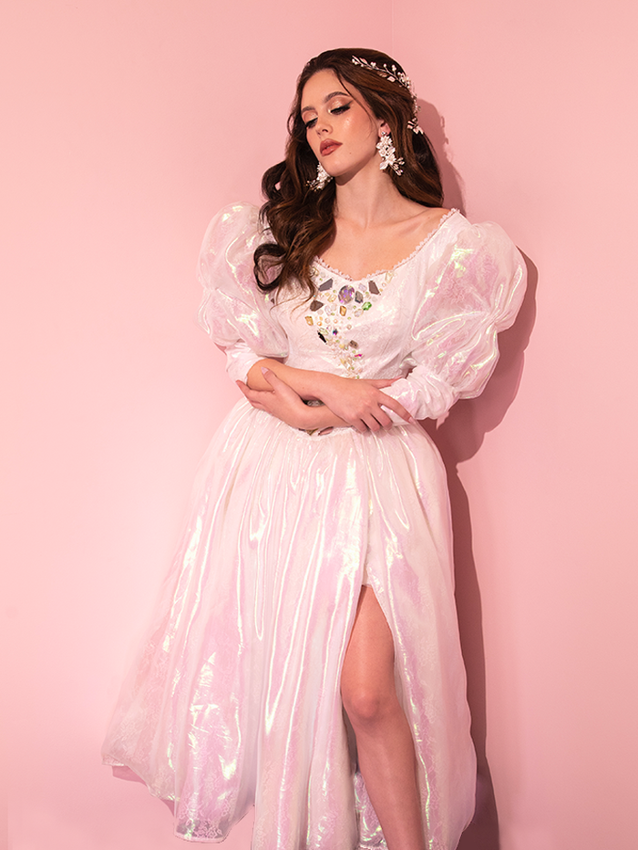 Behold the mesmerizing sight of a beautiful female model graced in the exquisitely rare LABYRINTH™ Sarah Goblin Ball Gown in Pearlescent White, a prized gem from the retro wonderland of Vixen Clothing.