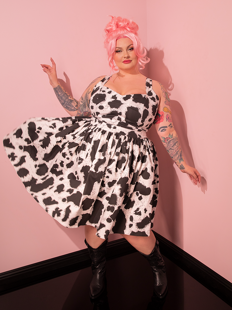 Stepping into the spotlight, the lovely female model embraces the essence of retro fashion as she flaunts the eye-catching Vixen Skater Skirt in Cow Print, a standout creation from Vixen Clothing's nostalgic collection.