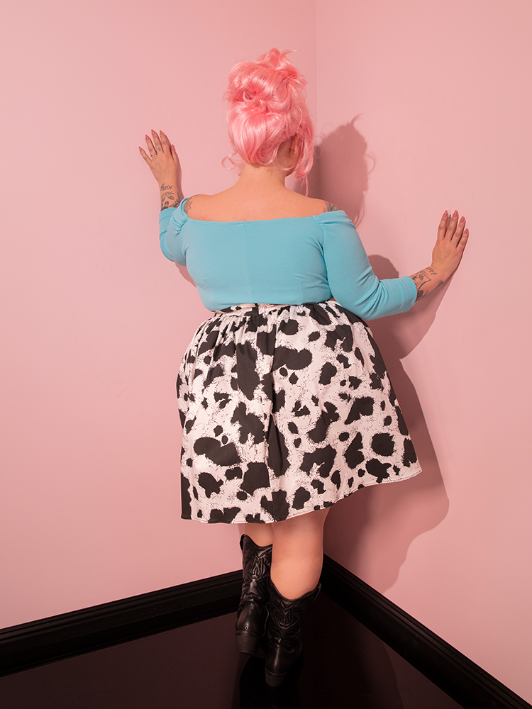 Mesmerizing onlookers with her captivating pose, the lovely female model brings the Vixen Skater Skirt in Cow Print to life—a remarkable testament to Vixen Clothing's dedication to timeless retro fashion.