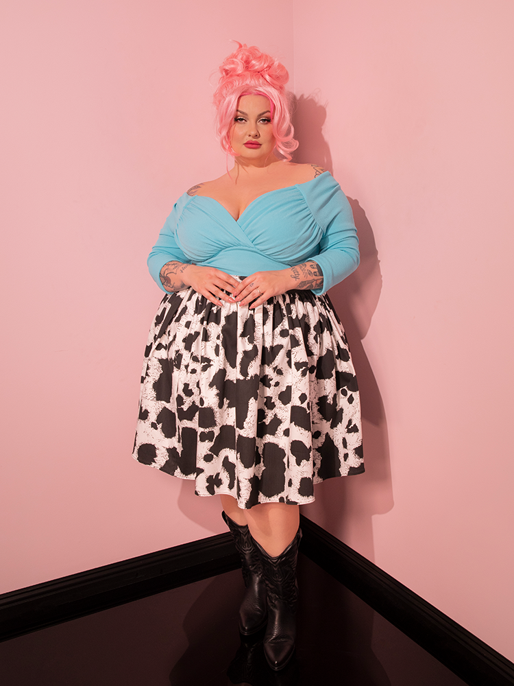 Time stands still as the lovely female model showcases the captivating Vixen Skater Skirt in Cow Print, a sartorial masterpiece that channels the retro spirit of Vixen Clothing's renowned fashion empire.