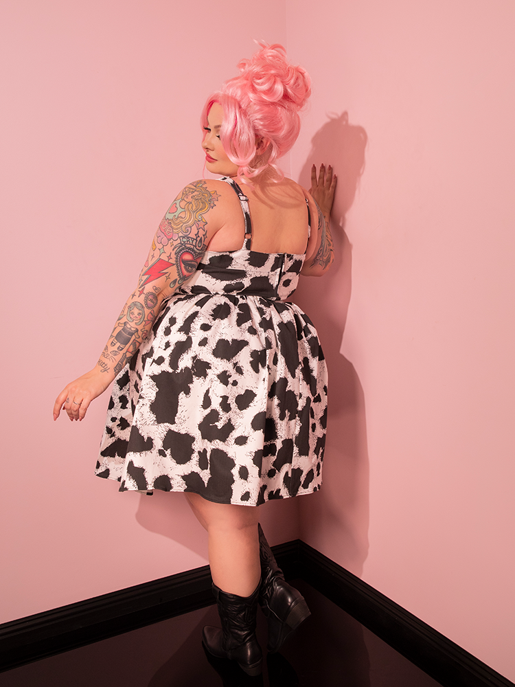 With an irresistible nod to the past, the female model captivates onlookers with her stunning pose, showcasing the Vixen Skater Skirt in Cow Print—an exquisite piece hailing from the retro-inspired world of Vixen Clothing.