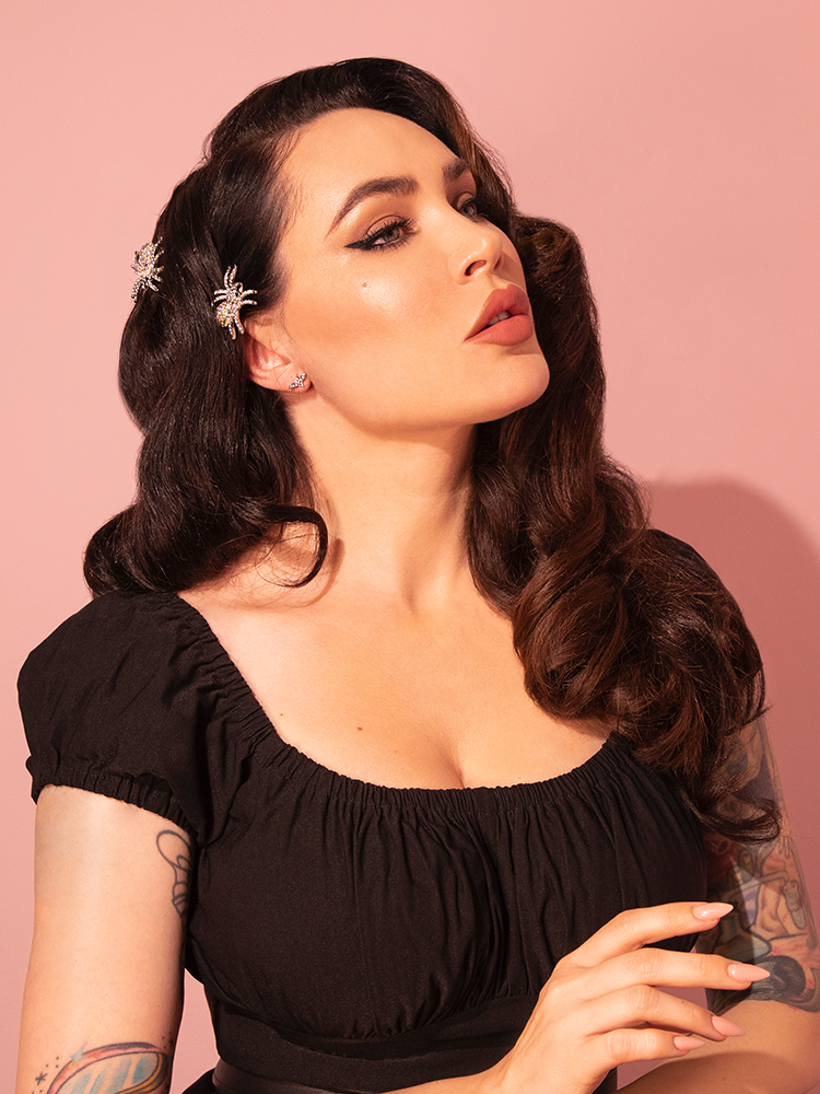 Micheline Pitt looking off camera to show off the side of her head with the Rhinestone Spider Hair Pins in Silver from retro clothing brand Vixen Clothing.