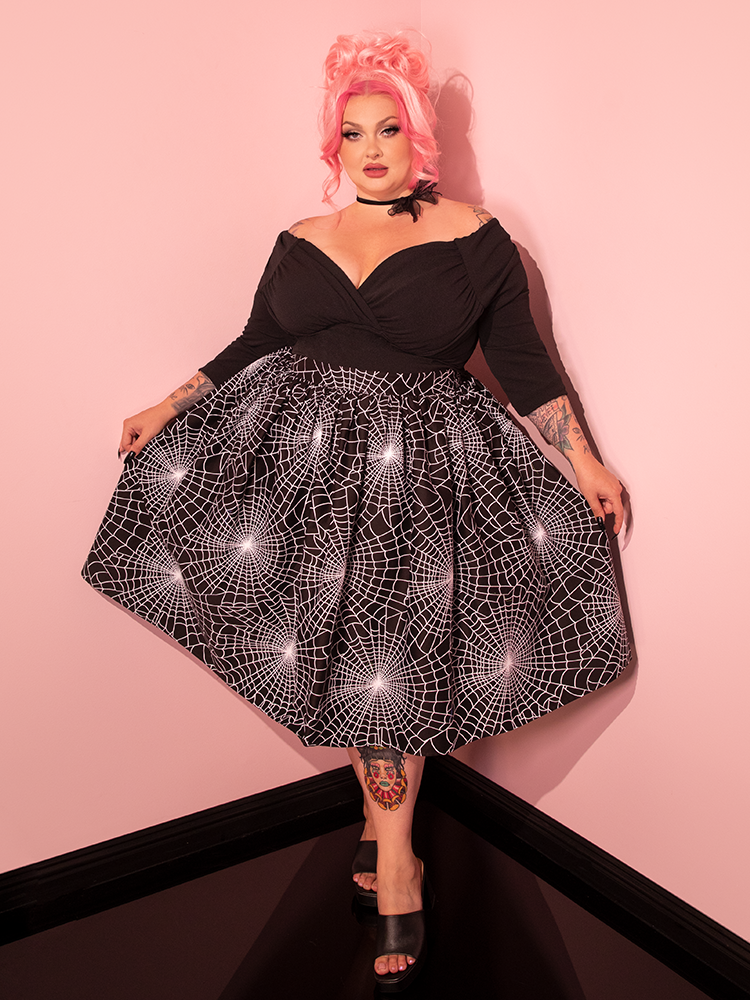 Behold the sheer elegance of a classic era, as our enchanting muse flaunts the Vixen Swing Skirt in Black Spider Web Print, the latest gem from the prestigious house of Vixen Clothing, known for their vintage vogue.