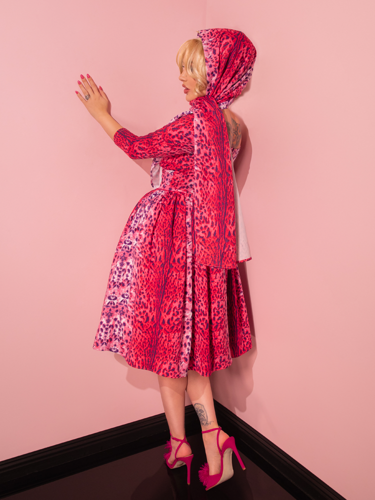 A stunning model, with a love for all things vintage, enchants as she showcases the Pink Leopard Print Starlet Swing Dress and Scarf from Vixen Clothing, a retro-inspired ensemble from the renowned retailer.