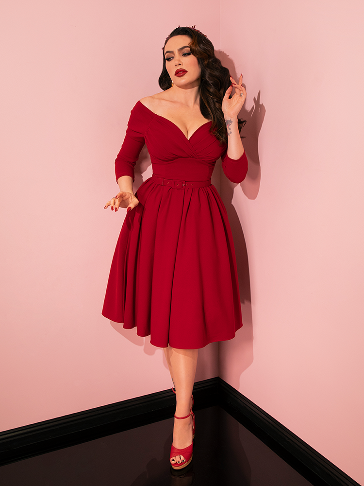 Dressed in the captivating Wrap Top in Red Velvet from Vixen Clothing, Micheline Pitt exhibits grace and style, emphasizing the brand's mastery in creating alluring retro clothing.