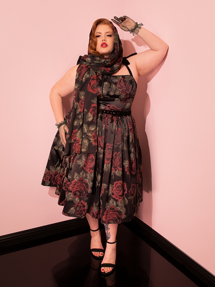 Modeling the retro-inspired 1950s Satin Swing Sundress and Scarf in Black Vintage Roses, the female model captivates with her diverse poses.
