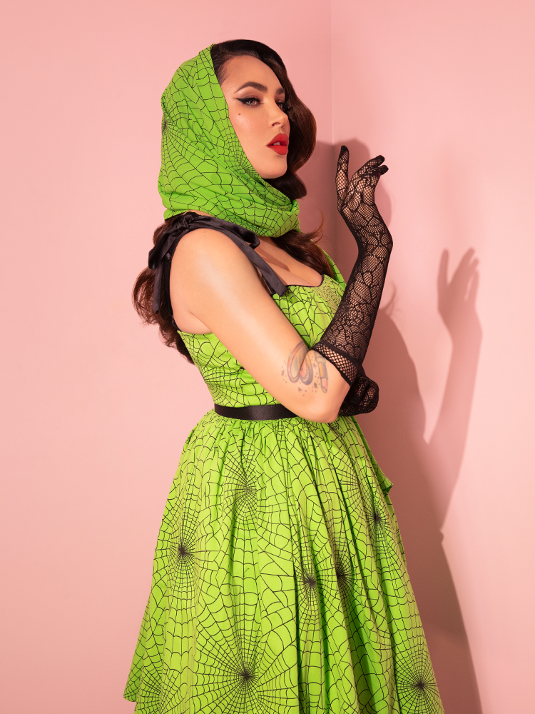 Experience the allure of yesteryear's fashion with Vixen Clothing's freshly unveiled 1950s Swing Sundress and Scarf, showcasing the Bold Slime Green Spider Web Print, now elegantly worn by a stunning female model.