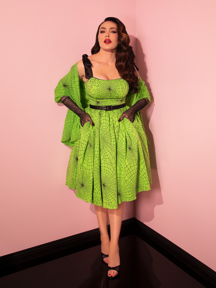 Vixen Clothing presents the 1950s Swing Sundress and Scarf in Eye-catching Slime Green Spider Web Print, beautifully showcased by a gorgeous female model, offering a taste of retro style.