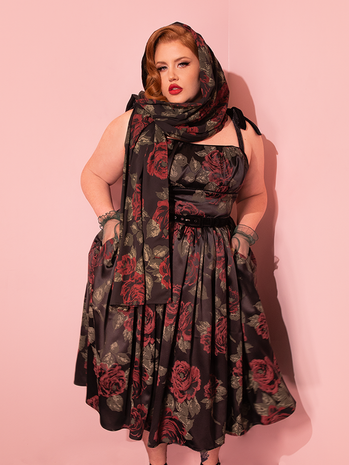 Step into the timeless allure of the 1950s Satin Swing Sundress and Scarf in Black Vintage Roses, a retro masterpiece by Vixen Clothing. Marvel at the grace of vintage models as they showcase this elegant ensemble.