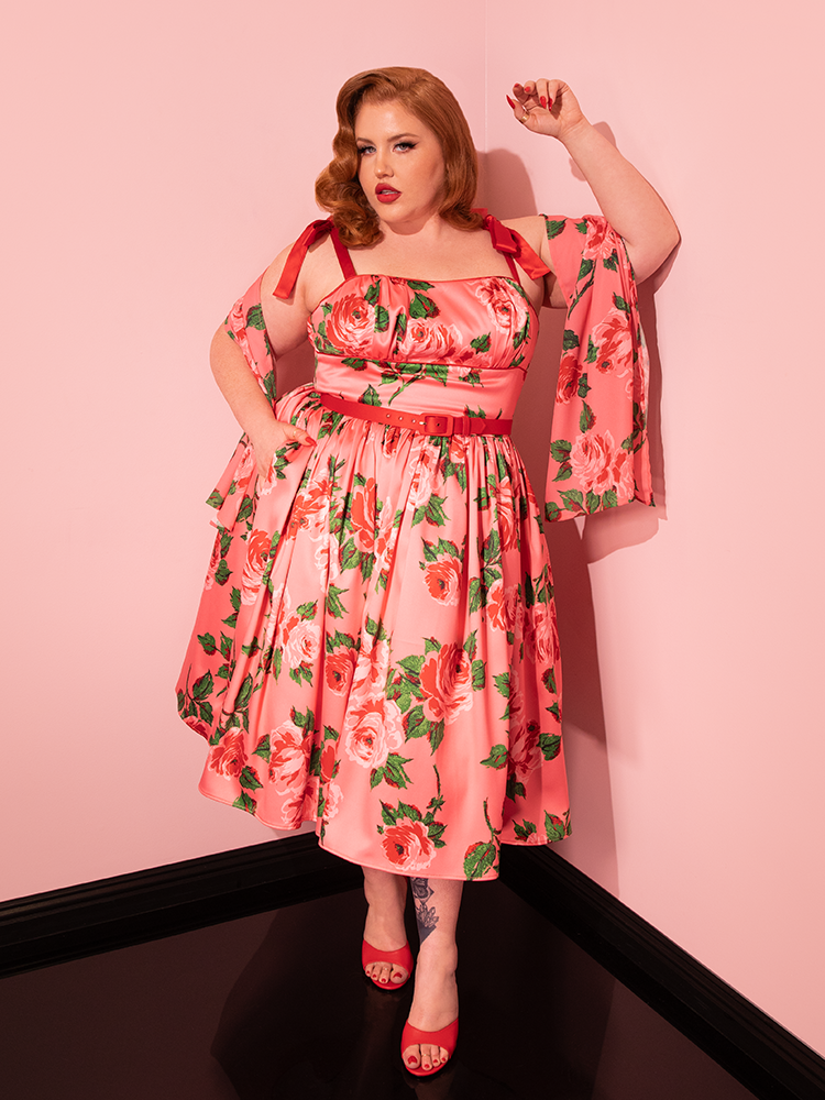 Step into the glamour of the past with Vixen Clothing's 1950s Satin Swing Sundress and Scarf in Pink Vintage Roses. Experience the nostalgia as vintage models bring this retro beauty to life on the runway.