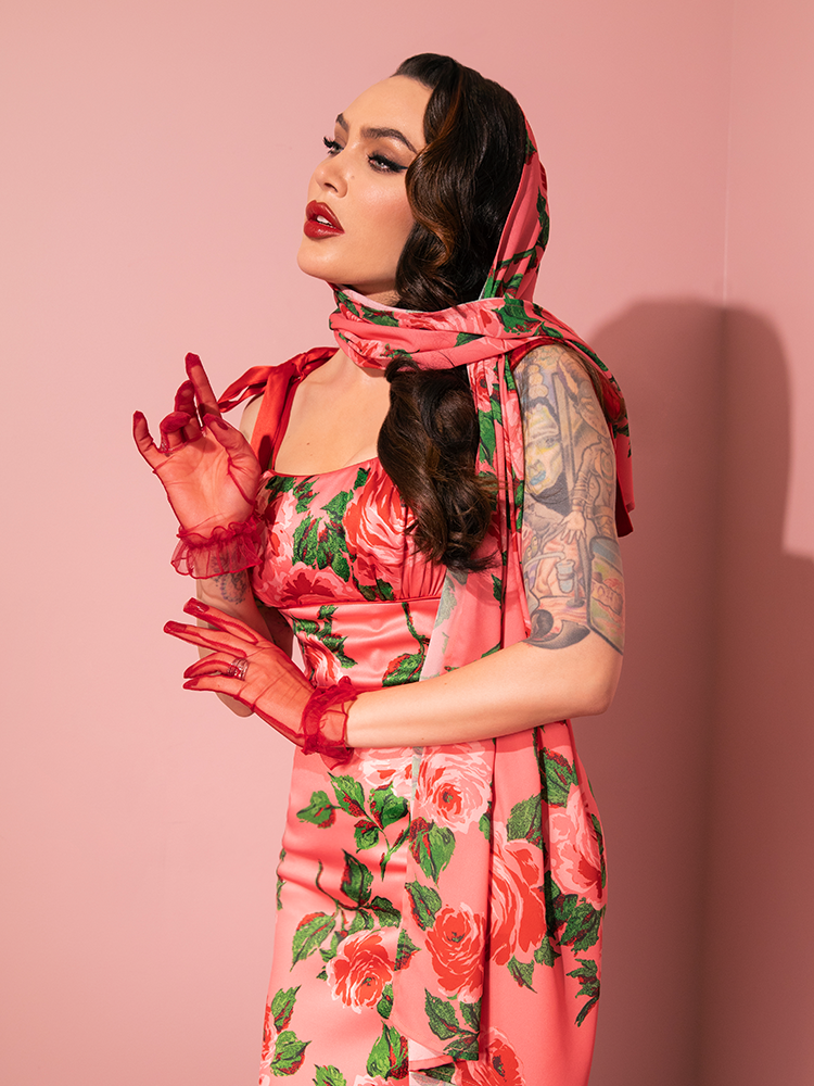 The 1950s Satin Wiggle Sundress and Scarf in Pink Vintage Roses steals the spotlight as female vintage models showcase a mix of fun and flirtation, embodying the signature style of Vixen Clothing's retro clothing.