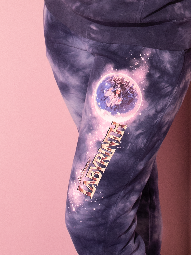 Step into a time warp as a stunning model embraces the essence of yesteryears, showcasing the LABYRINTH™ Goblin King Sweatpants in Midnight Blue Tie Dye, a rare gem from the treasure trove of Vixen Clothing's retro collection.