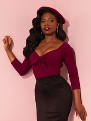The stunning model captivates in Vixen Clothing's Tie Me Up Top in Burgundy, showcasing the timeless allure of retro clothing with grace and sophistication.