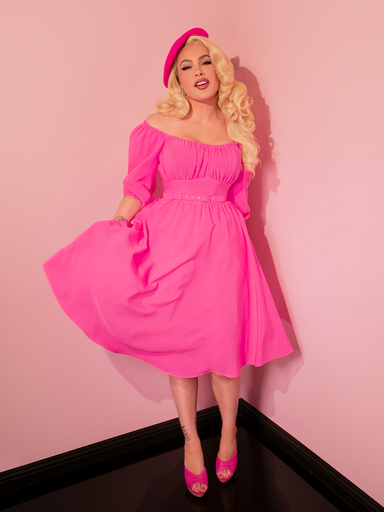 This retro dress, the Vacation Dress in Bright Pink, is designed to make you feel like a starlet on holiday, blending timeless style with a punch of color.