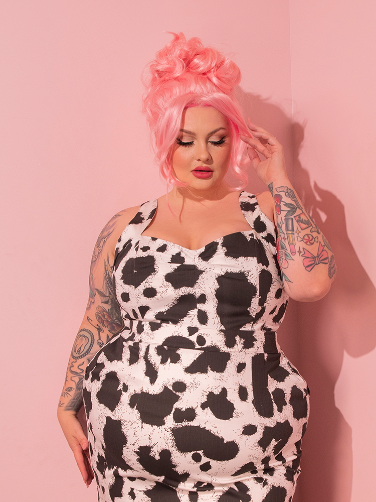Prepare to be transported to retro wonderland! The beguiling female model elegantly showcases the Vamp Top in Cow Print, an alluring piece designed by the renowned retro brand, Vixen Clothing.