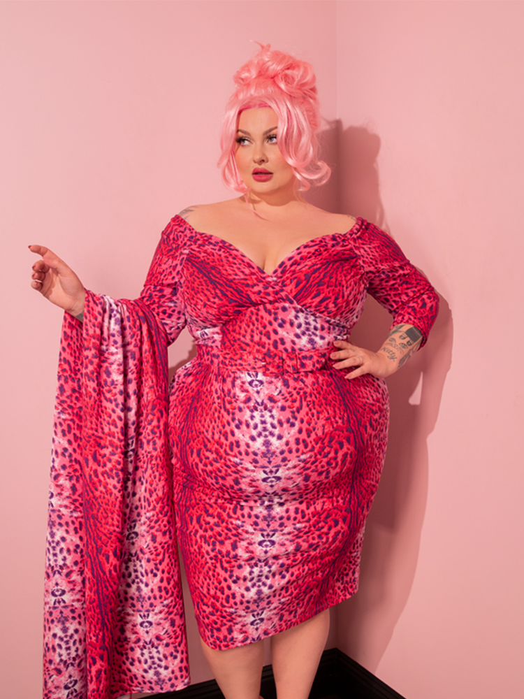 Prepare to be captivated by a mesmerizing female model wearing the Pink Leopard Print Starlet Wiggle Dress and Scarf, exuding the essence of retro fashion from Vixen Clothing.