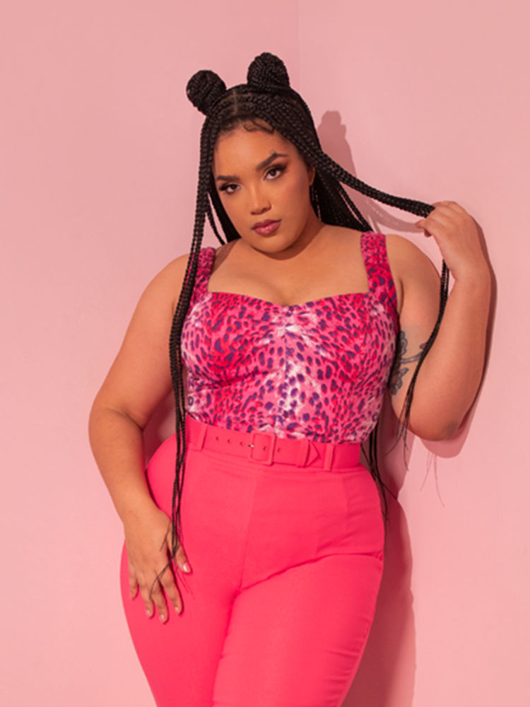 With a vintage touch, a stunning female model exudes allure while showcasing the Pink Leopard Print Vamp Top, a captivating ensemble from Vixen Clothing, a brand celebrated for its retro-inspired designs.