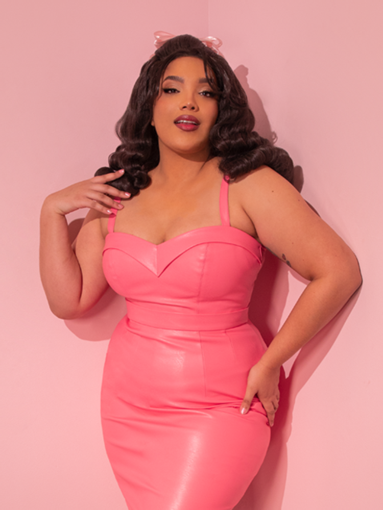 Immerse yourself in the world of retro glamour as you behold the breathtaking model, exuding elegance in the Bad Girl Maneater Top in Flamingo Pink Vegan Leather, an emblem of timeless beauty from Vixen Clothing, a pioneer in vintage fashion.