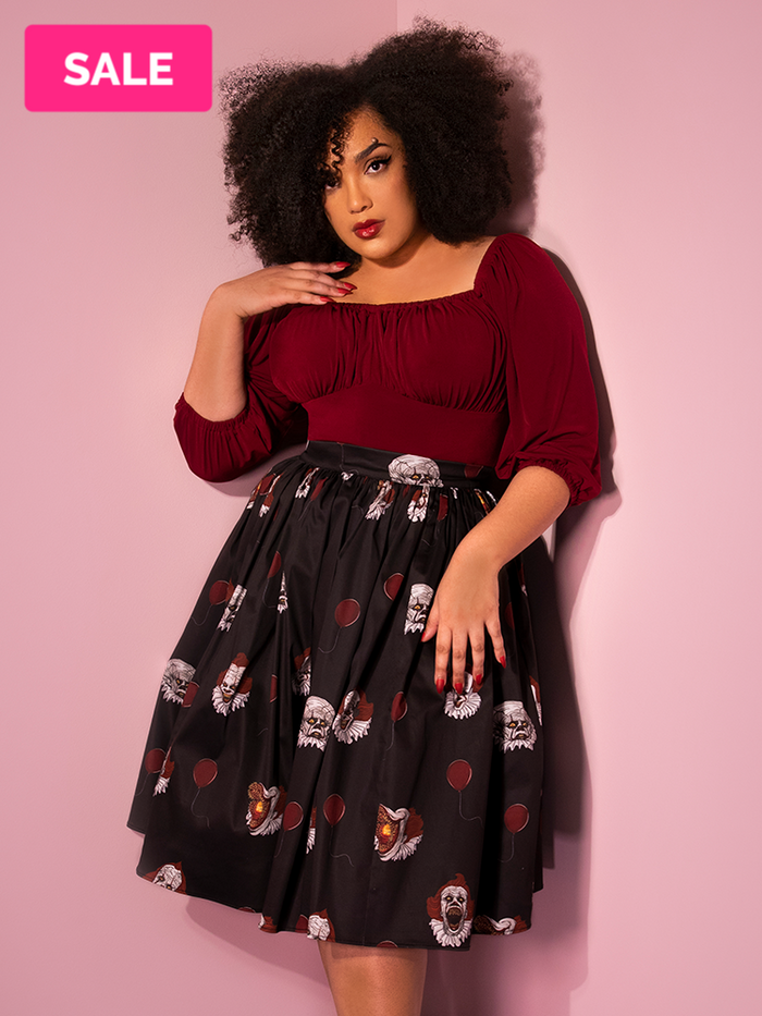 With her hand on her shoulder, Ashleeta models the Pennywise swing skirt in black by Vixen Clothing.