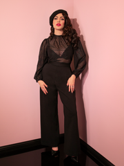 Full length shot of Micheline Pitt standing in an all-black outfit including the Vacation Pants in Black Ponte, black sheer long-sleeve top and black beret.