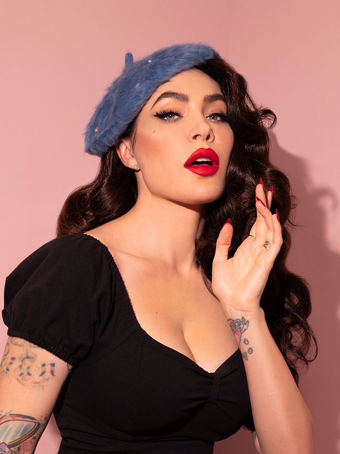 Micheline Pitt posing in a black retro top and the Vintage Style Beret with Rhinestones in Sunset Blue.