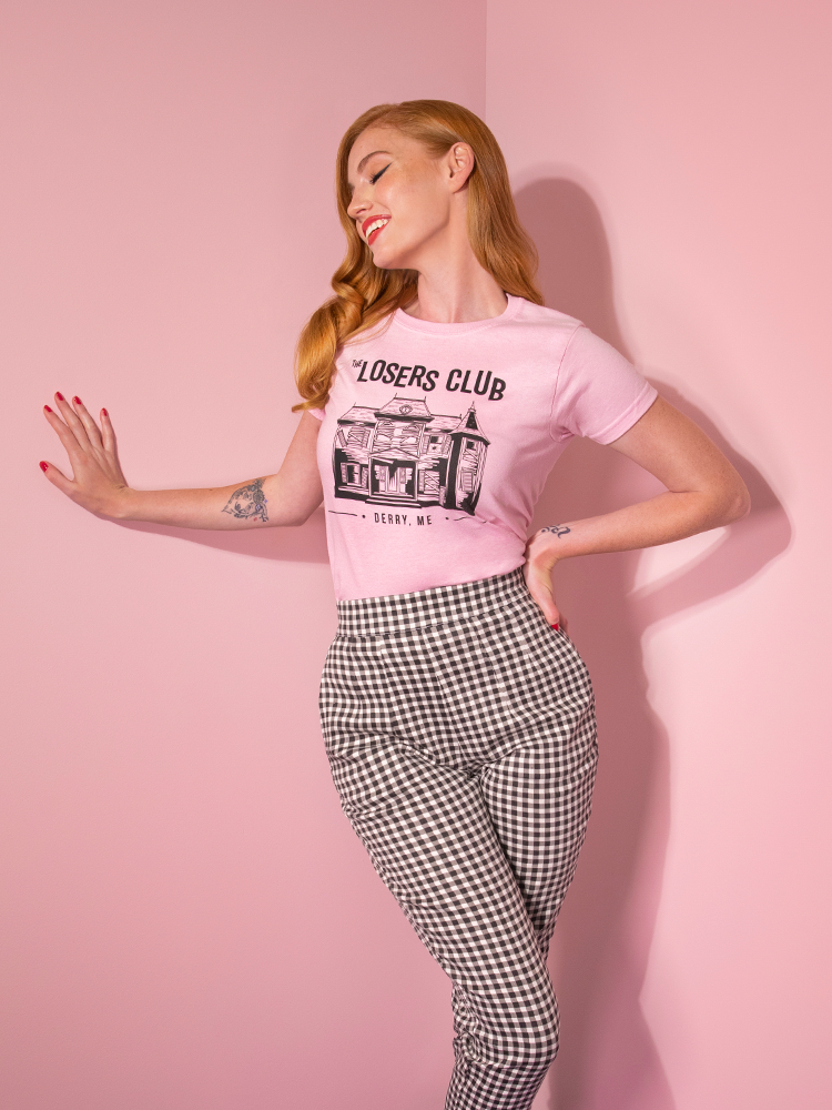 Looking away from camera and smiling, model Emily wears the Losers Club pink tee by Vixen Clothing.