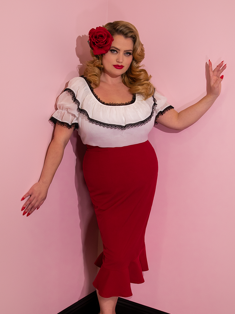 A closeup of Blondie with a red rose in her hair modeling the Vixen flutter skirt in red paired with a white peasant top.