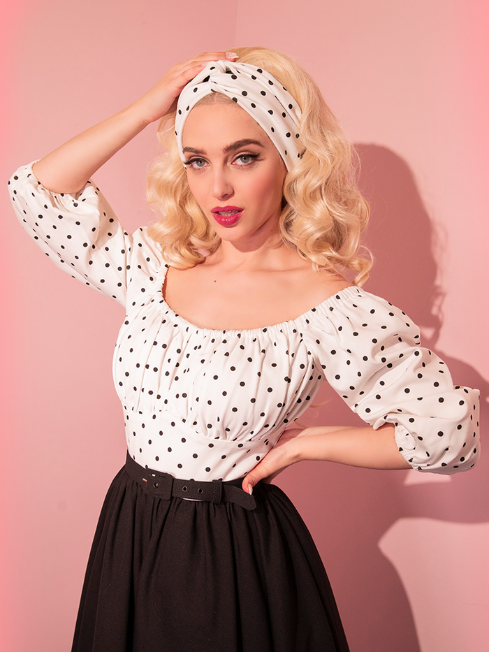 Sofia wearing the Vintage Style Knot Headband in Black Polka Dot with a matching black polka dot top and black skirt. 