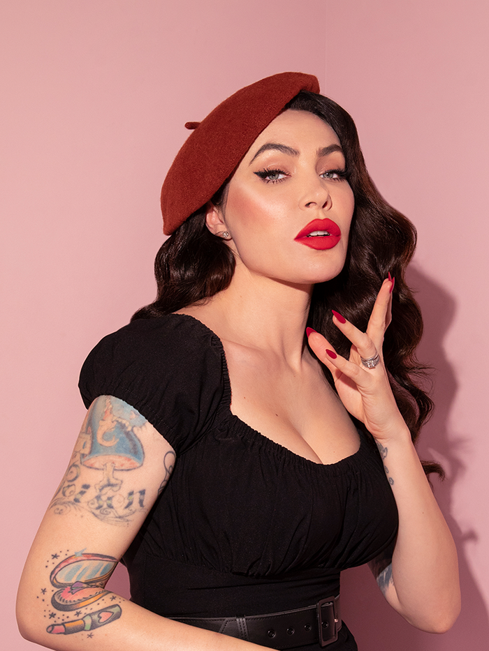 Micheline Pitt photographed from the waist up wearing the Vintage Style Beret in Rust from Vixen Clothing.