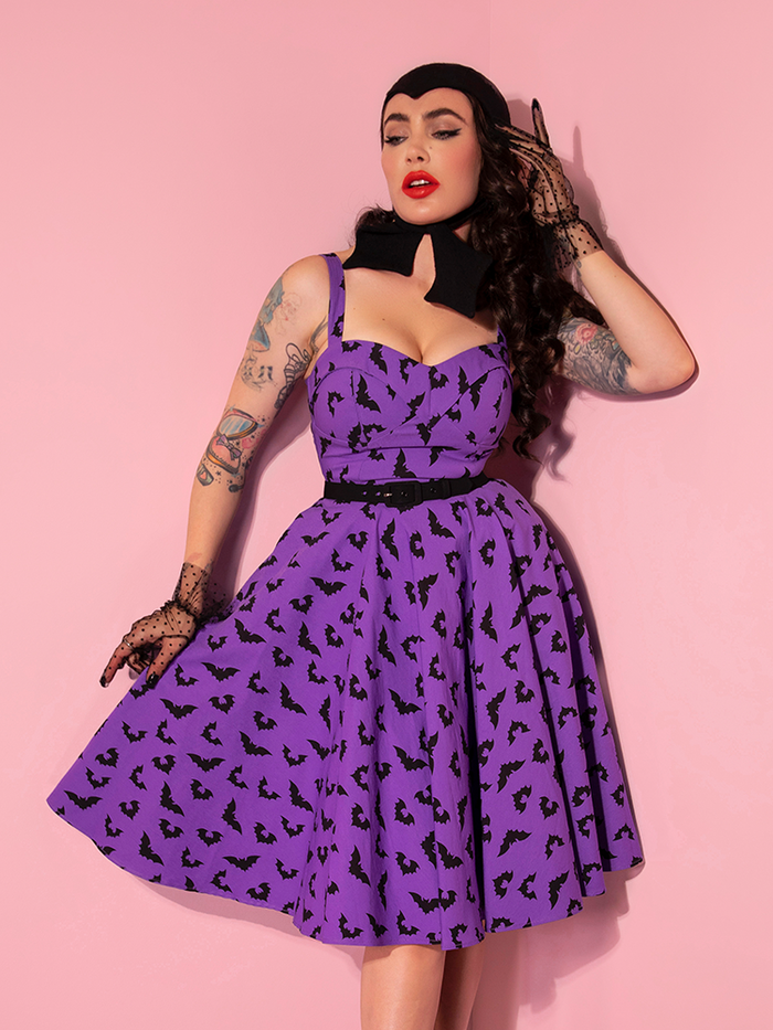 Micheline Pitt standing in the Maneater Swing Dress in Bat Print from Vixen Clothing.