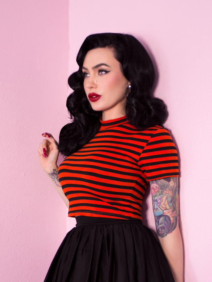 A closeup of Micheline Pitt modeling the Bad Girl crop top in orange and black stripes from Vixen Clothing.
