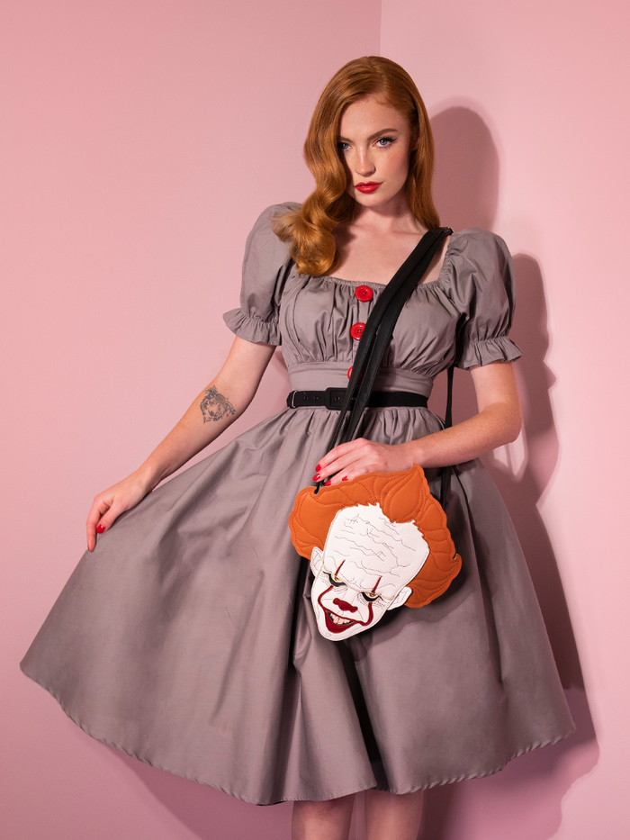Model Emily holds her skirt while wearing the Pennywise babydoll dress from Vixen Clothing.