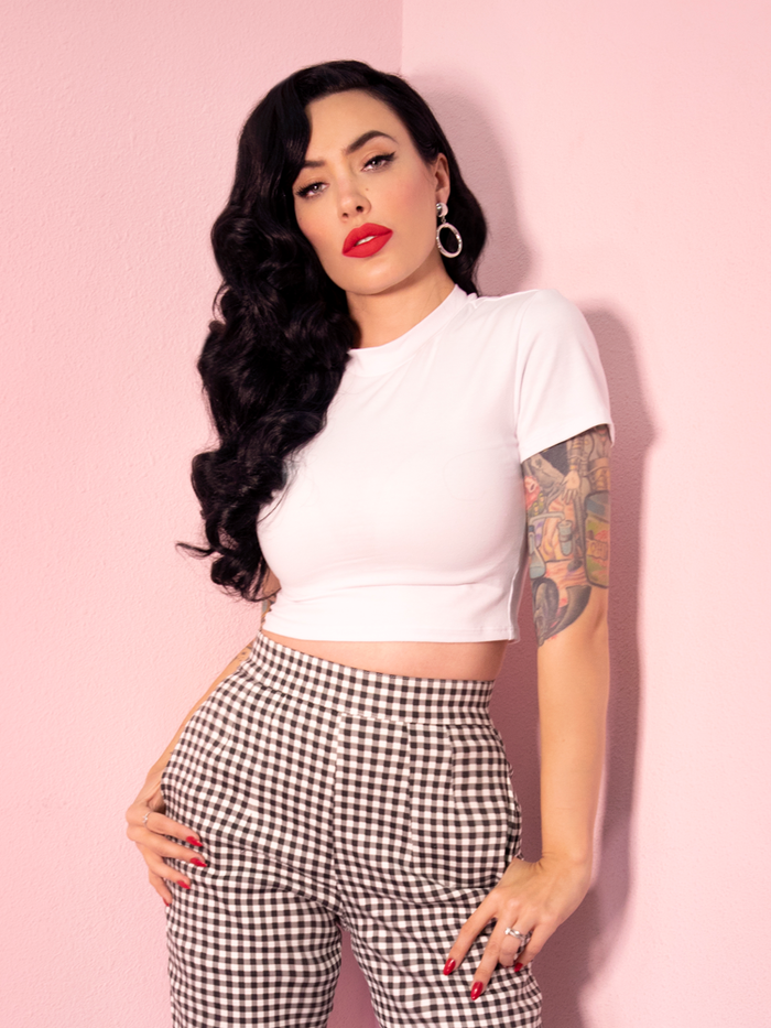 A closeup of Micheline Pitt modeling the Bad Girl crop top in white paired with gingham cigarette pants.