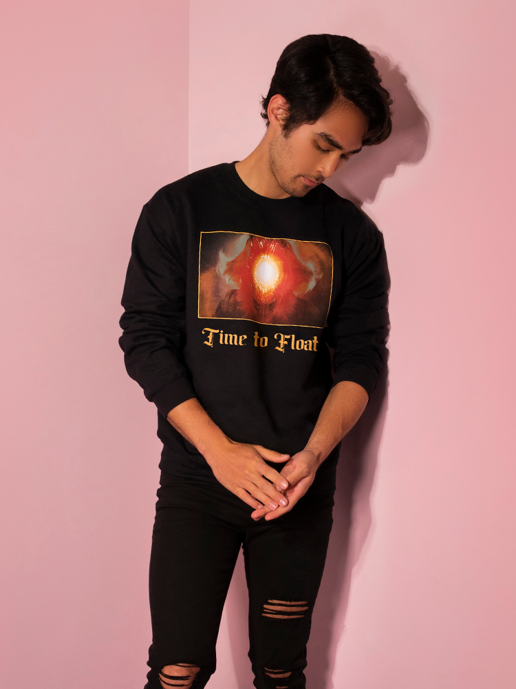 Looking down with his hands together, Ethan models the Time to Float sweatshirt by Vixen Clothing.