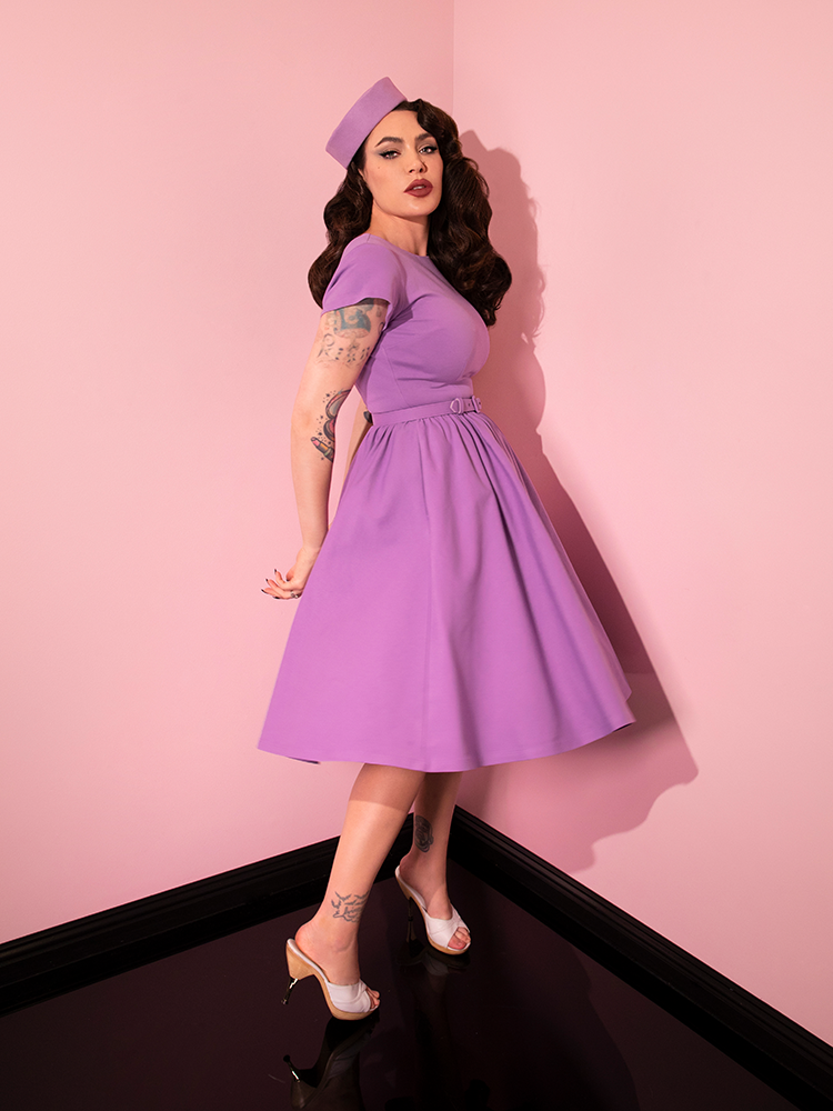 Micheline Pitt turned to the side to give a profile shot of the Avon Swing Dress in Lilac.