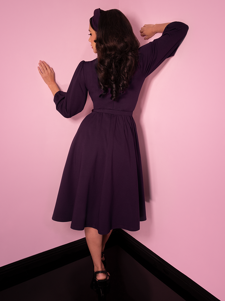 Back shot of Milynn Moon modeling the Bawdy Swing Dress in Eggplant from Vixen Clothing.
