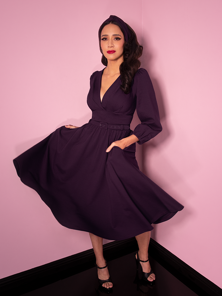 Milynn Moon photographed mid-twirl wearing the Bawdy Swing Dress in Eggplant from Vixen Clothing.