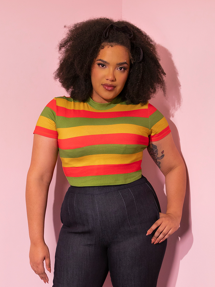 Half length shot of model wearing the Bad Girl Crop Top in Orange/Yellow/Avocado Stripes with matching dark denim for a casually retro style outfit.