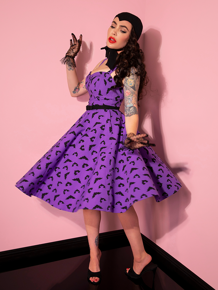Side shot of Micheline Pitt twirling in the Maneater Swing Dress in Bat Print from retro dress company Vixen Clothing.
