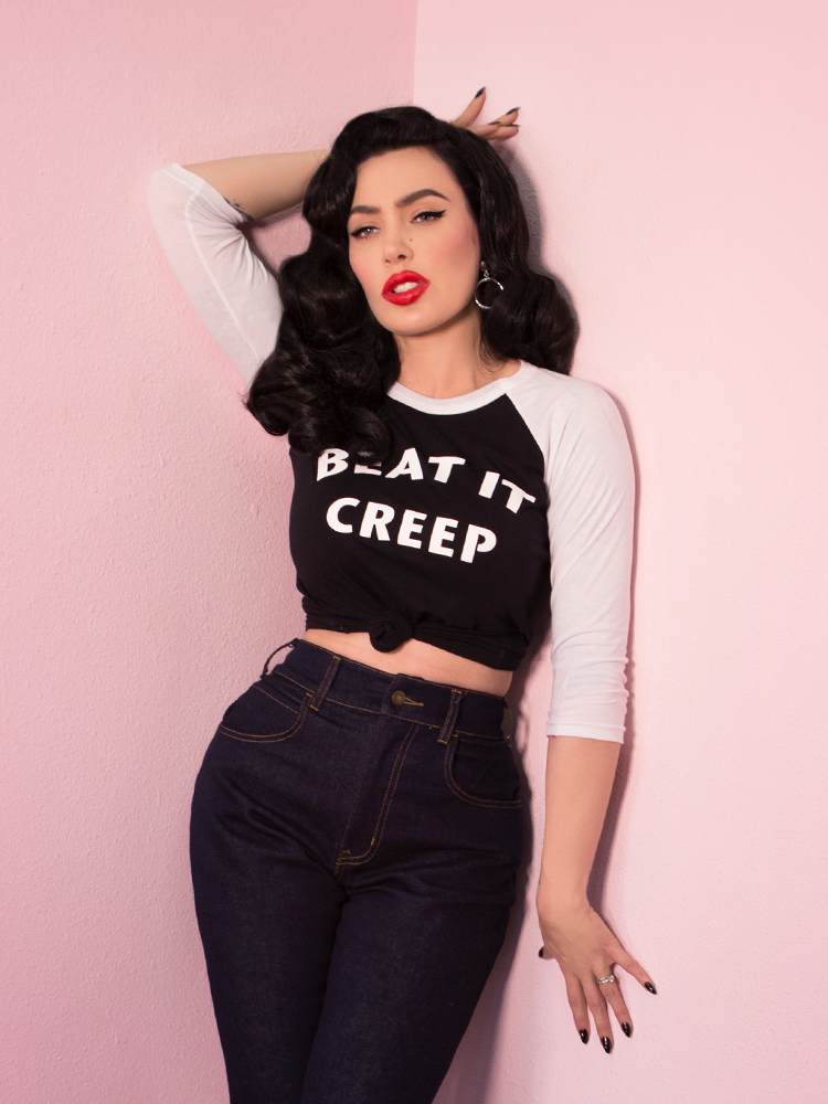 With her hand behind her head, Micheline Pitt models the Beat It Creep raglan t-shirt by Vixen Clothing.