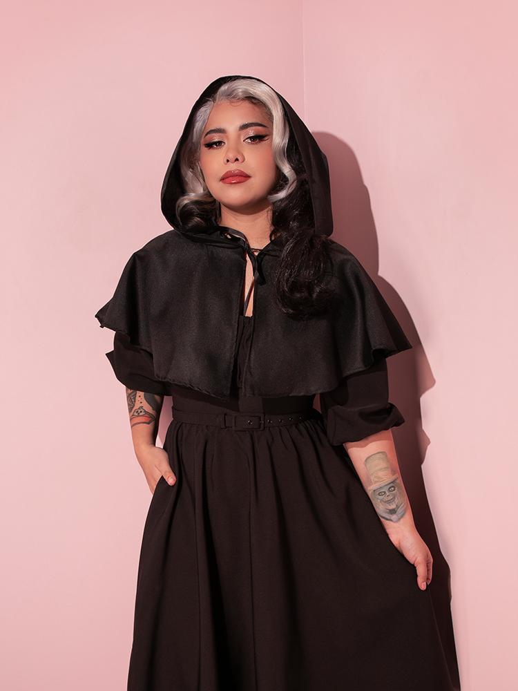Margo posing in an all black outfit highlighted by the all-new Hooded Witch Capelet in Black.