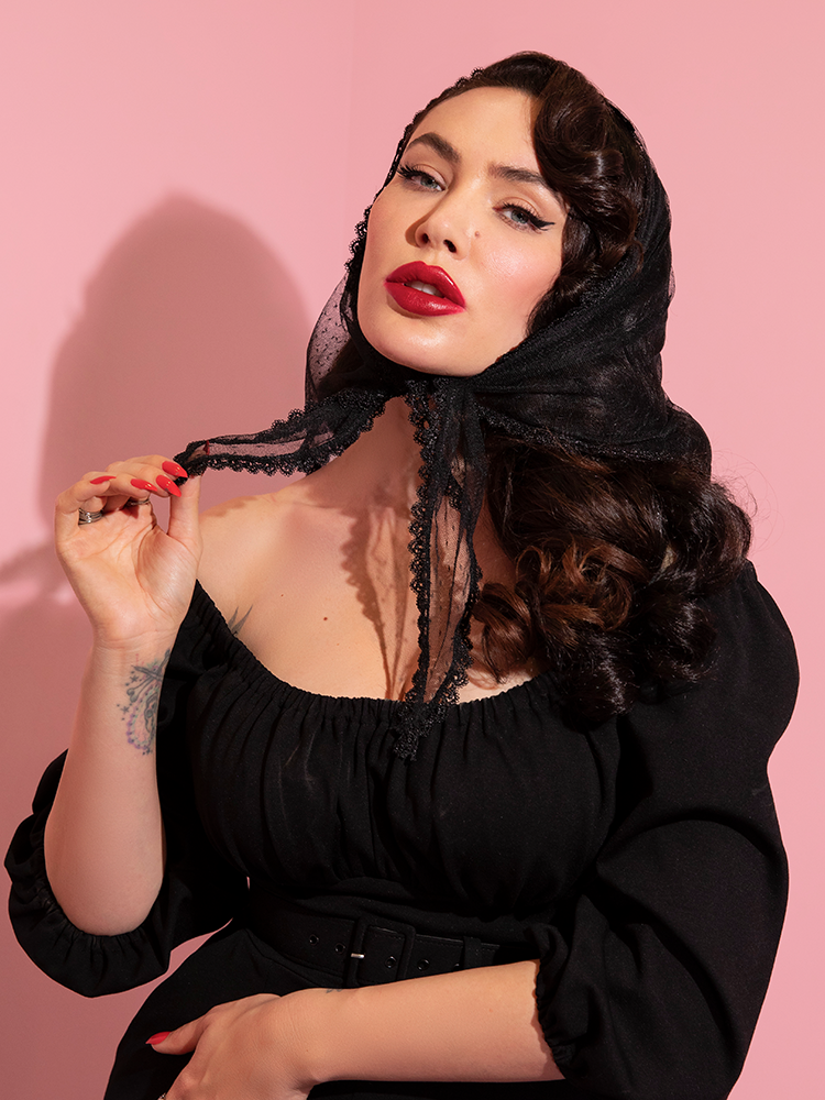 The Vintage Style Black Lace Scarf, being modeled by Micheline Pitt, is paired with a retro style low-cut top also from Vixen Clothing.