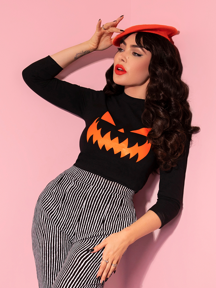 Micheline Pitt posing in the Pumpkin King 3/4 Sleeve Top in Black and Orange from vintage clothing maker Vixen Clothing.